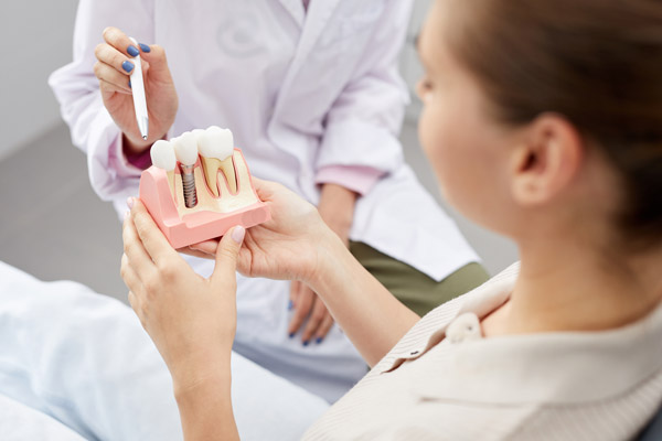 Image of a dental professional showing a patient that a dental implant is a good fit for her.