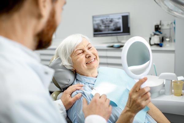 Elderly woman enjoying her new smile with implant-supported dentures from Surprise Oral & Implant Surgery in Surprise, AZ